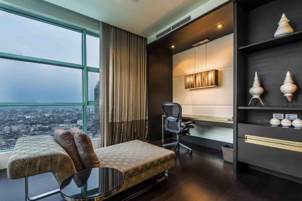 A window-side desk and office chair share the room with a daybed and city-facing glazing.