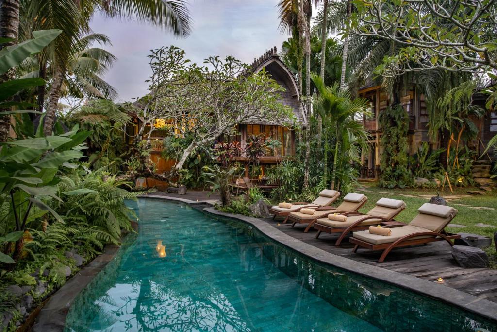 a pool with lounge chairs next to a house at Aryaswara Villa Ubud in Ubud