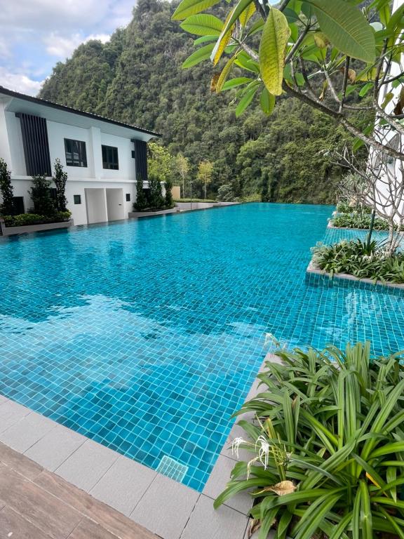 a blue swimming pool with a mountain in the background at Onsen Suits HJM @ Sunway Ipoh in Ipoh