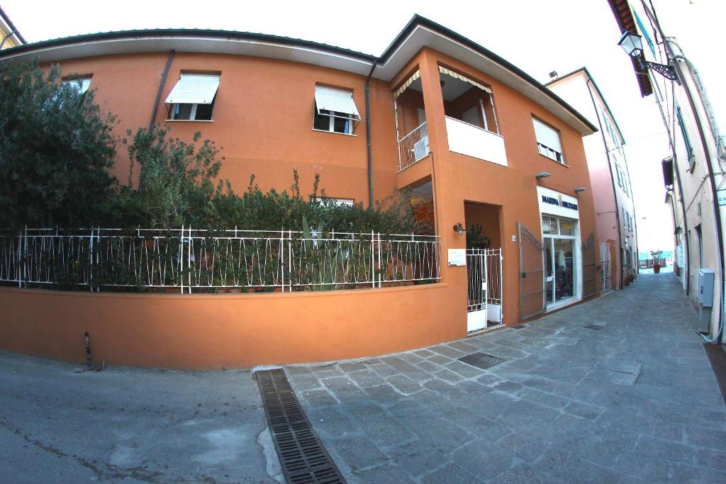 duży pomarańczowy budynek z płotem przed nim w obiekcie Soggiorno Tagliaferro w mieście Marciana Marina