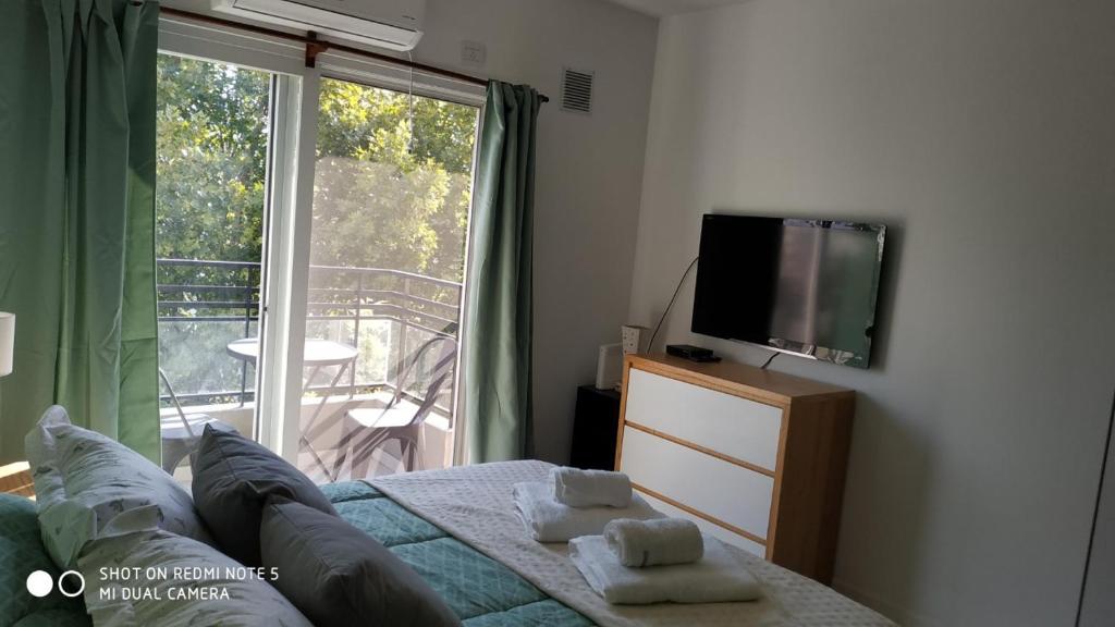 a bedroom with a bed and a television and a balcony at Murillo Star con Cochera "Movistar Arena a 4 Cuadras" in Buenos Aires