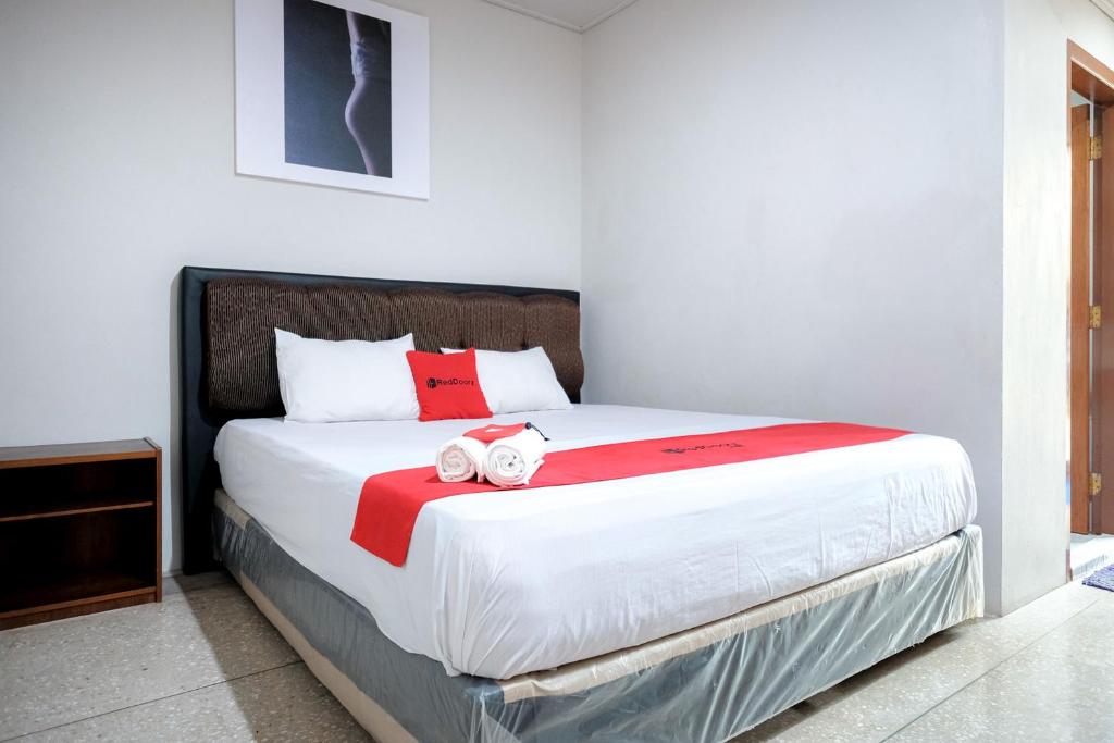 a bedroom with a large bed with red and white sheets at Capital O 93602 Hotel Tempoa Inn in Jambi