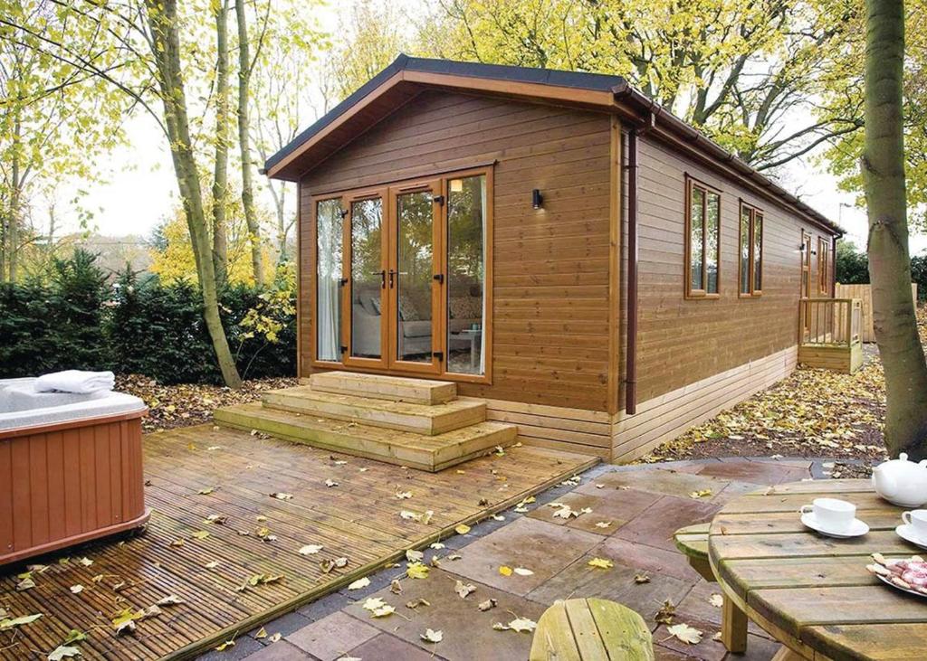 a small cabin in a garden with a patio at Jamies Cragg Holiday Park in Welburn