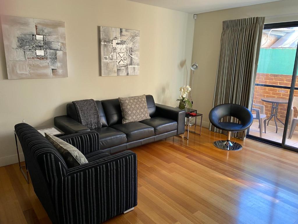 a living room with a black couch and a chair at Parklane Apartments in Fremantle