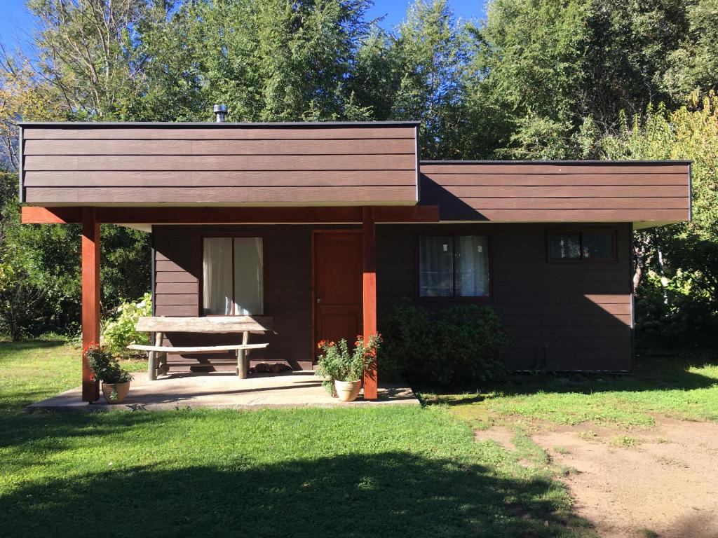 una pequeña casa con una mesa de picnic delante de ella en Cabañas Pucontours, en Pucón