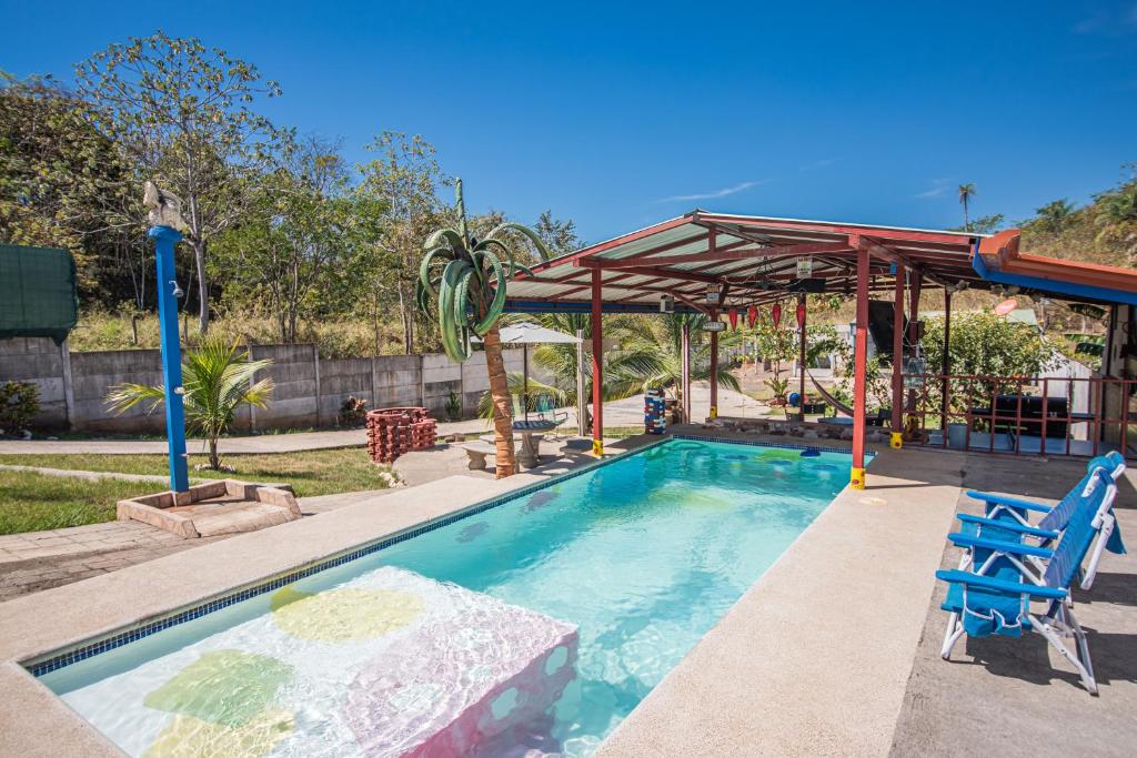 una piscina con un pabellón y 2 sillas azules en Casa, 3 dormitorios, piscina, rancho, cocina, minibar, pingpong, 9 personas en Capulín
