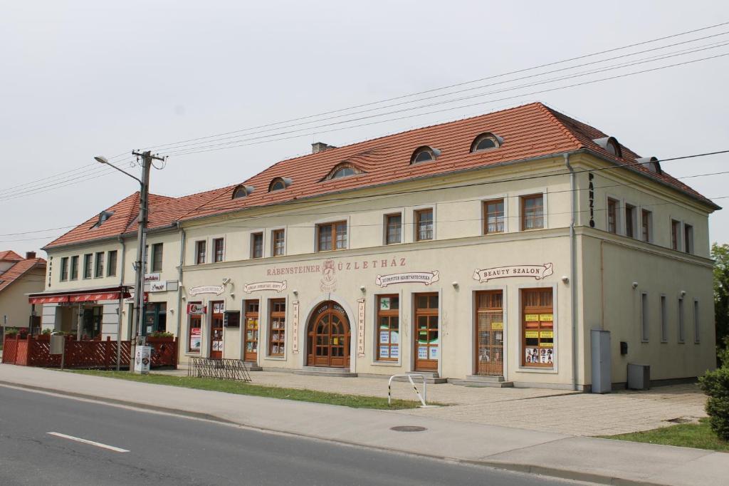 un grand bâtiment blanc sur le côté d'une rue dans l'établissement Rábensteiner Panzió, à Fertőd