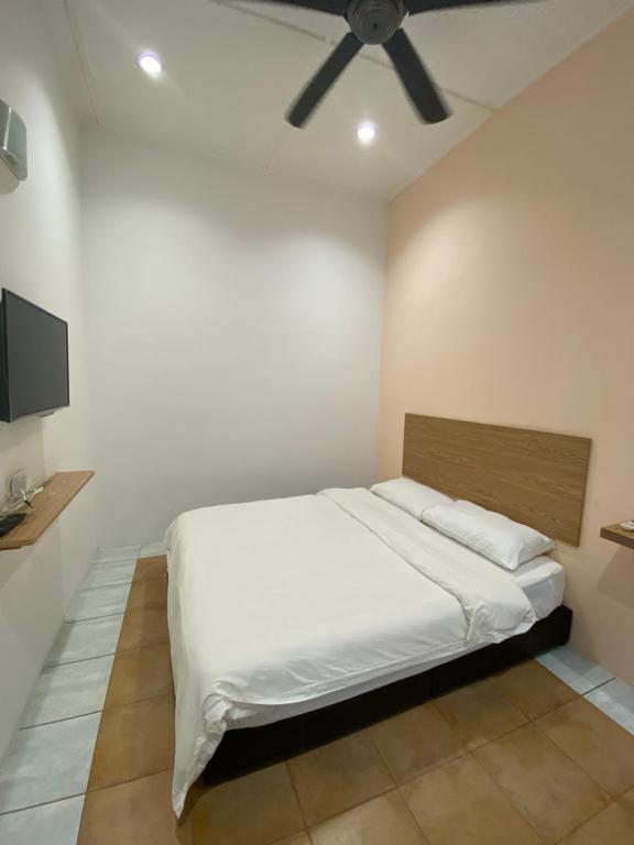 a bedroom with a white bed with a ceiling fan at Raintown inn taiping in Taiping