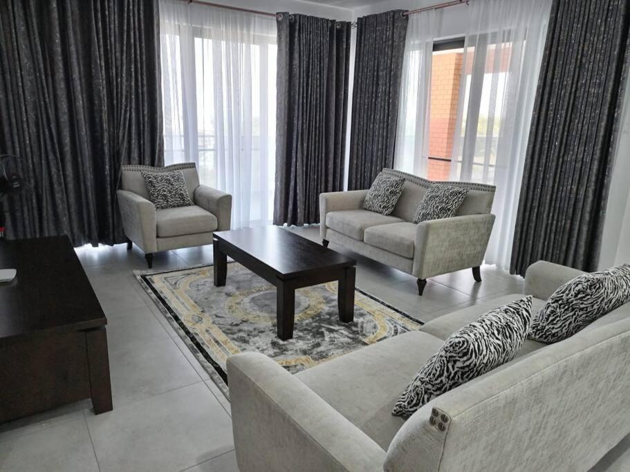 a living room with two couches and a coffee table at Georgia Apartments - A Cozy Brand New Apt… in Mombasa