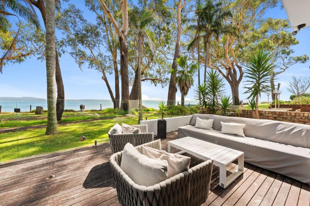 a living room with a couch and chairs on a deck at Ebb and Flow Sandy Point Road 70 in Corlette