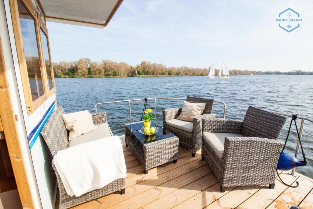 una terraza con sillas y una mesa en un barco en WOHLFÜHLBOOT Hausboot - Festlieger im Hafen Bad Saarow - WC an Bord, Dusche an Land, en Bad Saarow