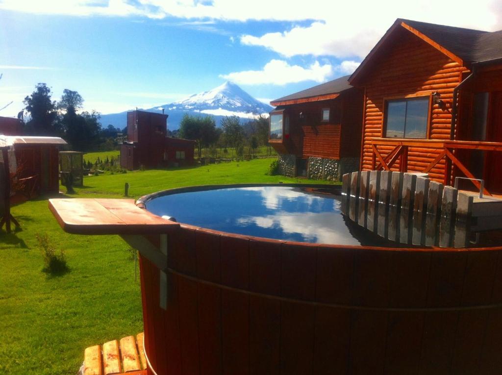 uma piscina em frente a uma casa com uma montanha em Cabañas Anulen em Los Riscos
