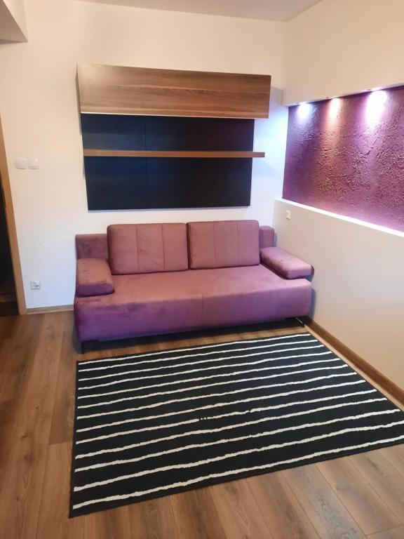 fioletowa kanapa w salonie z dywanem w obiekcie Maja Apartment w mieście Sopot