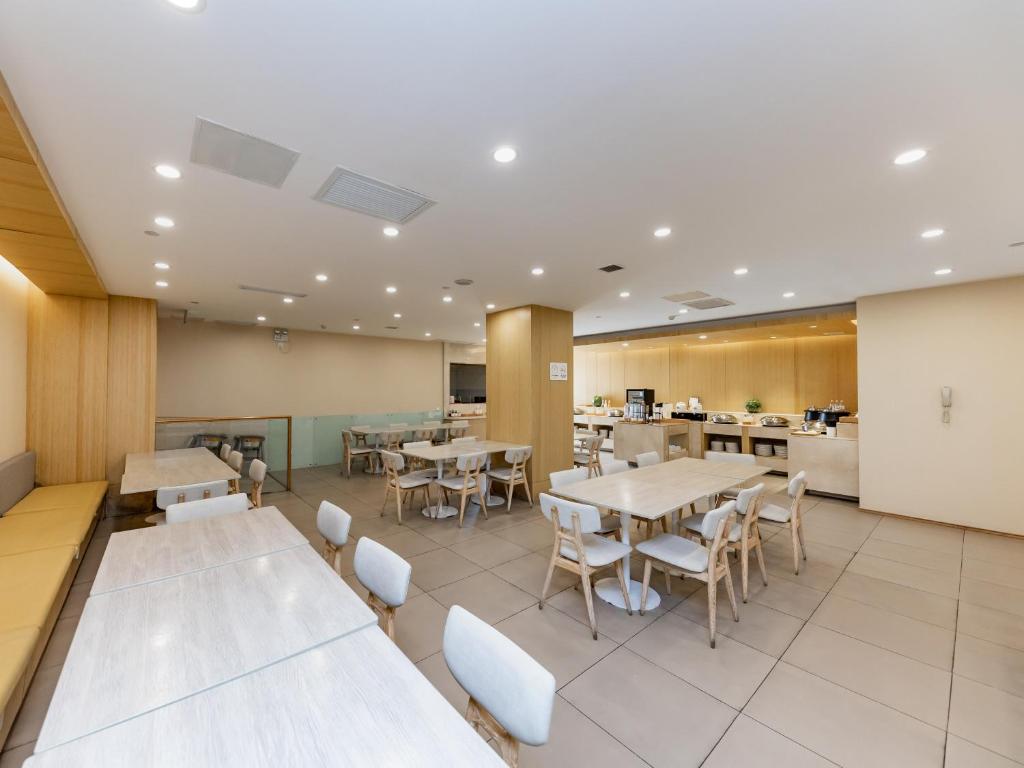 a dining room with tables and chairs and a kitchen at JI Hotel Nanjing Hongqiao Zhongshan North Road in Nanjing