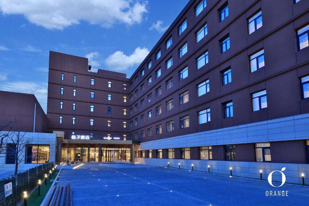 a large building with a parking lot in front of it at Orange Hotel Beijing Summer Palace in Beijing