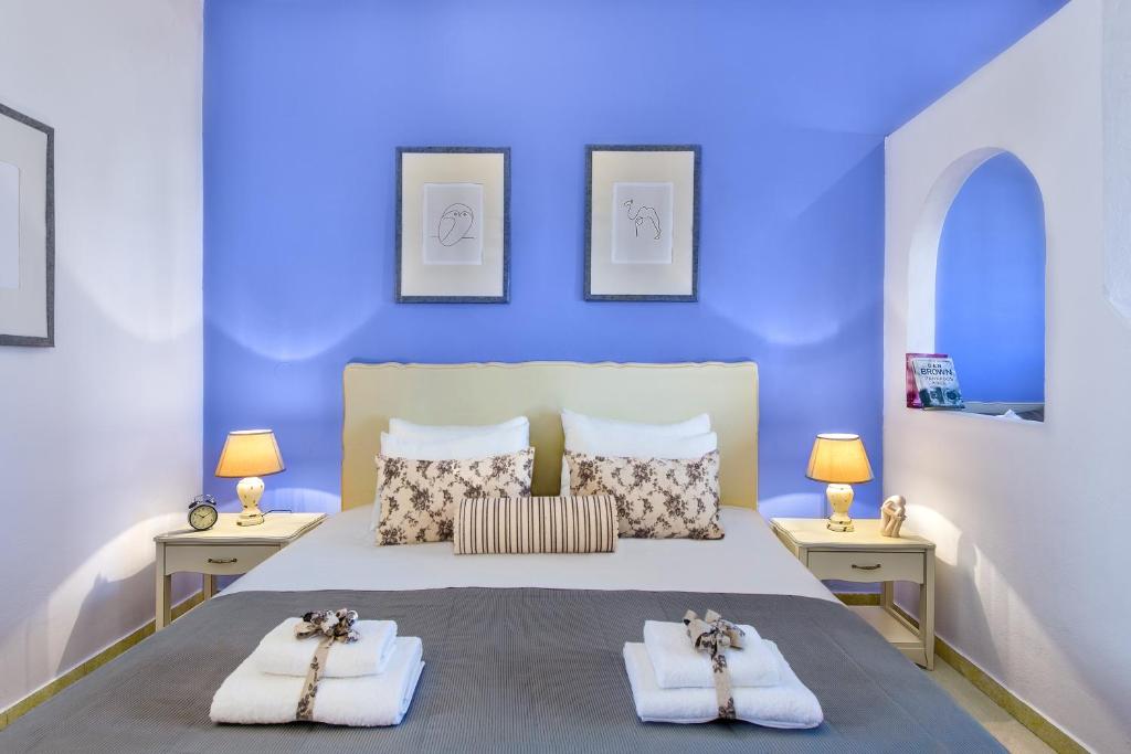 Agrimia Holiday Apartments في بلاتانياس: غرفة نوم زرقاء مع سرير عليه مناشف