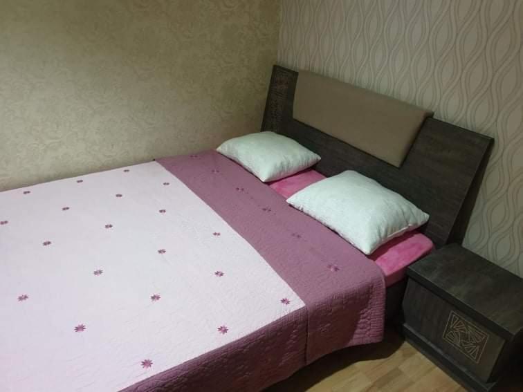 1 dormitorio con 1 cama con sábanas moradas y almohadas blancas en Срочно Сдаётся!!!, en Tiflis