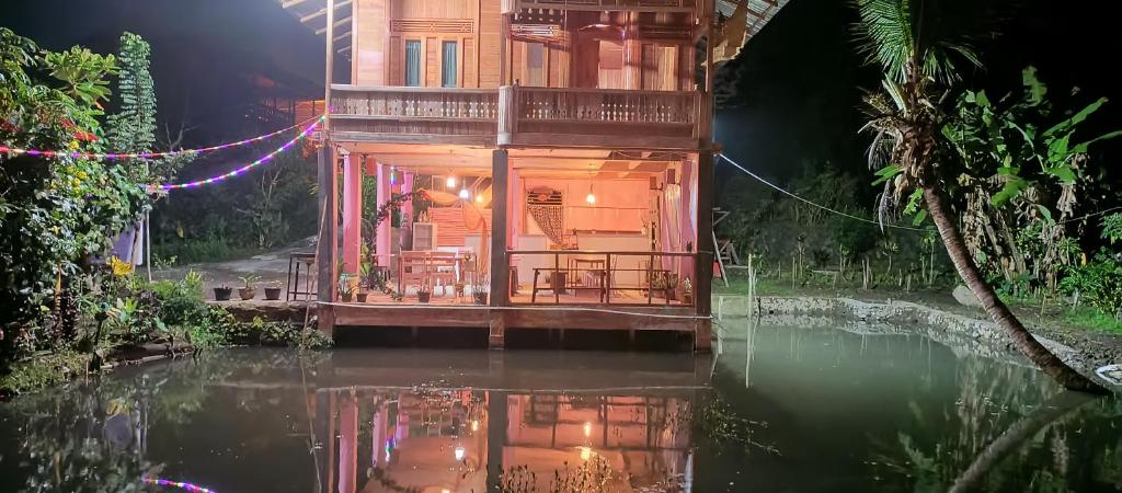 una casa en medio de un río por la noche en Talaga Tomohon Home Stay and Fishing Pond, en Tomohon
