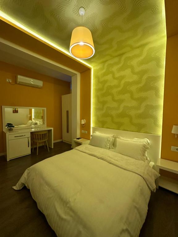 1 dormitorio con 1 cama grande y pared amarilla en AL BON Park, en Berat