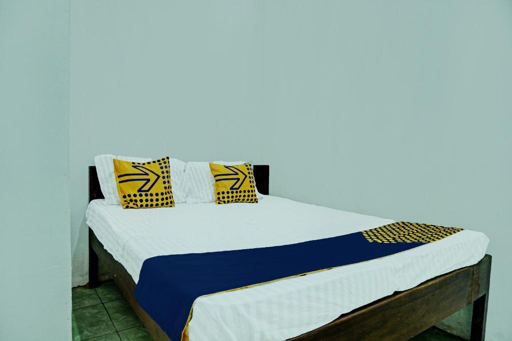 ein Bett mit blauen und gelben Kissen darauf in der Unterkunft SPOT ON 92301 Penginapan Indola 