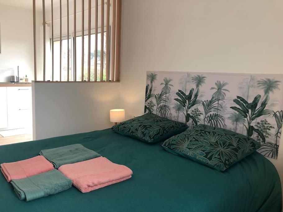 - un grand lit vert avec trois oreillers dans l'établissement Studio avec Piscine, à Saint-Médard-en-Jalles