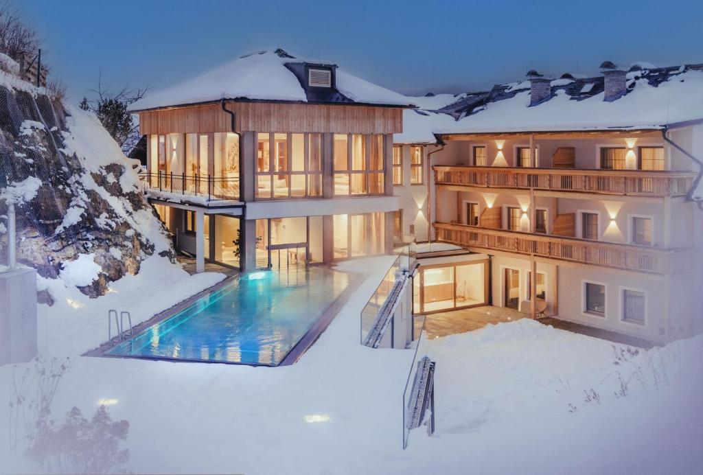 ein Haus mit Pool im Schnee in der Unterkunft Hotel Weissenstein in Sankt Michael im Lungau