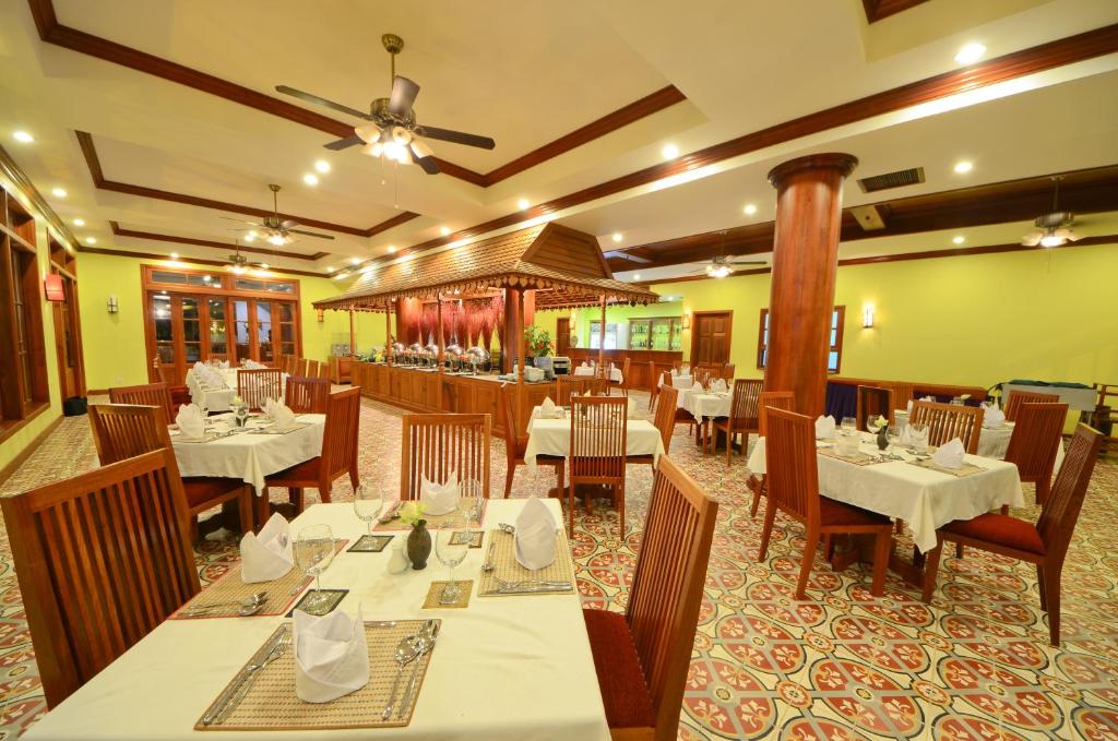 a restaurant with white tables and wooden chairs at Royal Crown Hotel & Spa in Siem Reap