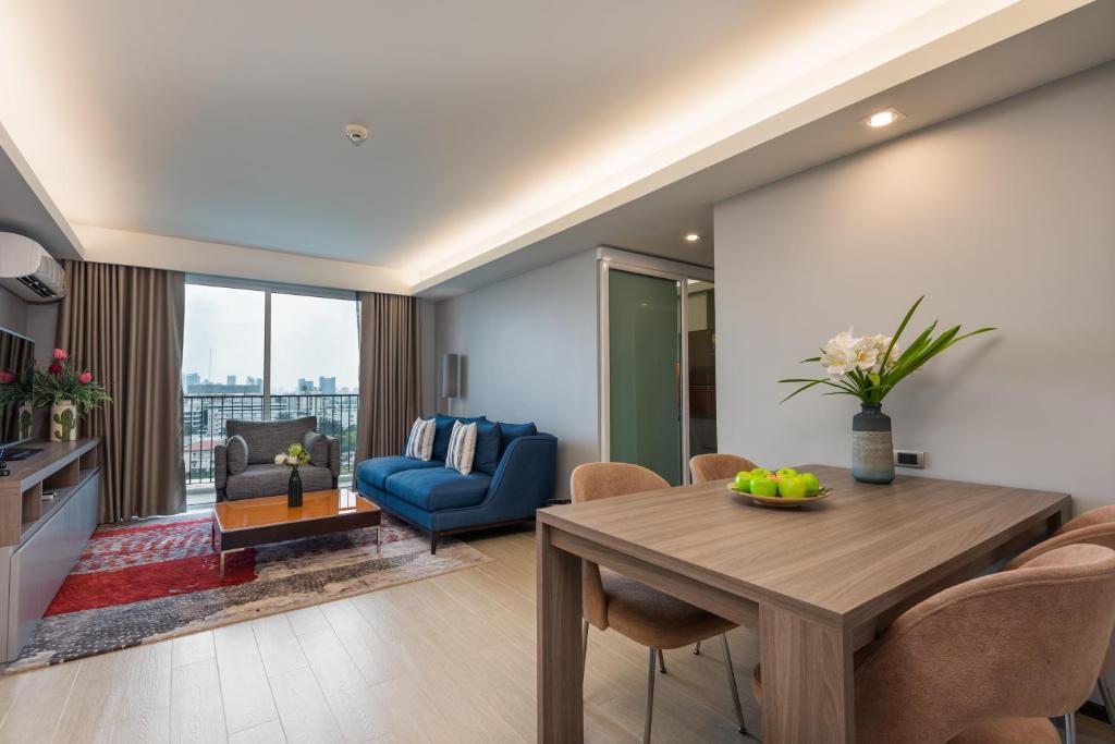 A spacious living area with a blue sofa, dining table, balcony window and city outlook.