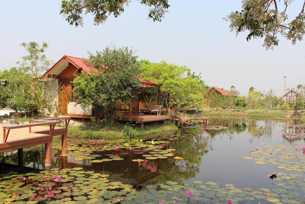 a house next to a pond with water lilies at OYO 75419 Baan Suan Mulberry Farmstay in Hua Hin