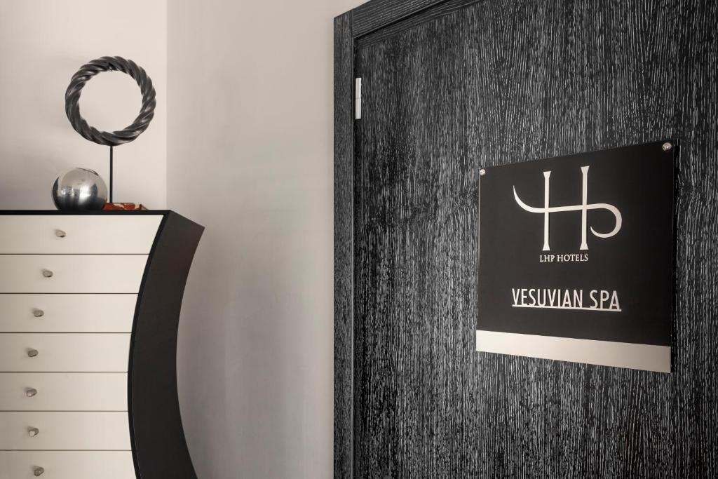 a black door with a sign on it next to a dresser at LHP Napoli Palace & SPA in Naples