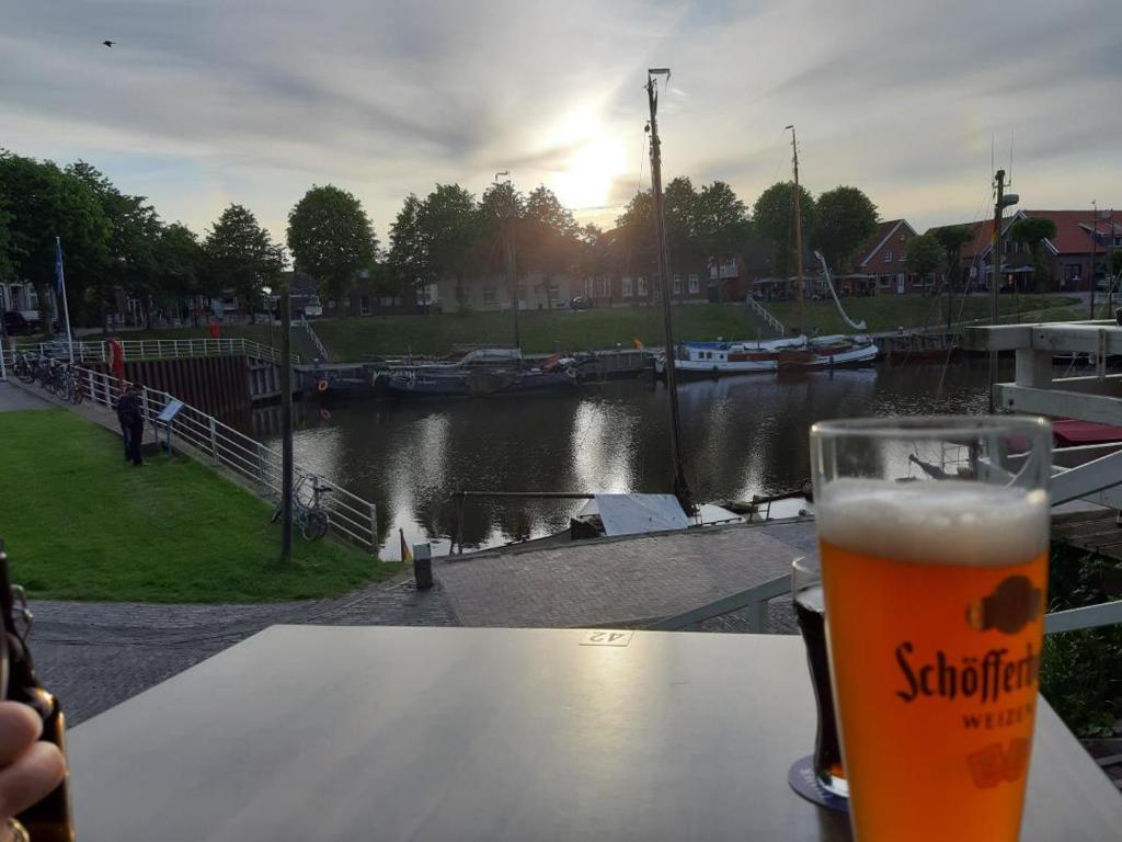 a glass of beer sitting on a table next to a river at NEU! Fewo Merle mit Balkon in Carolinensiel