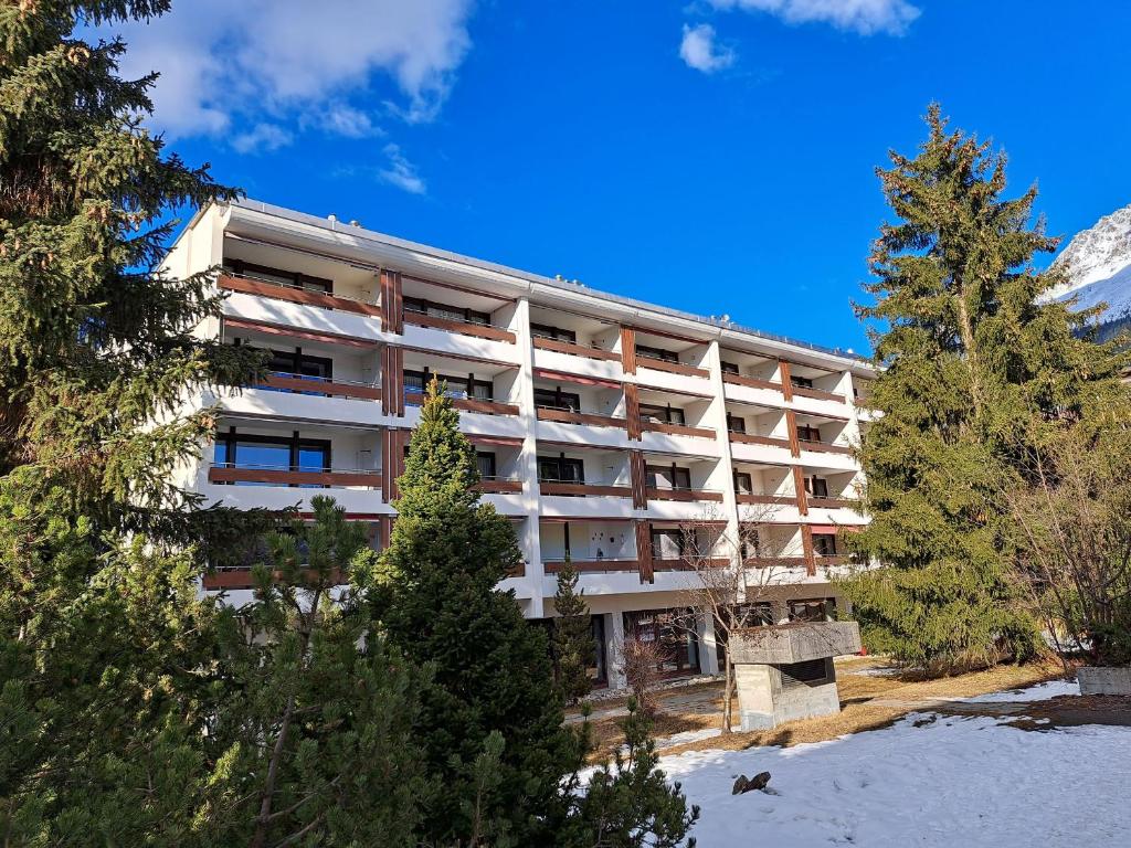 an apartment building in the mountains with trees at Astoria (175 Cl) in Lenzerheide