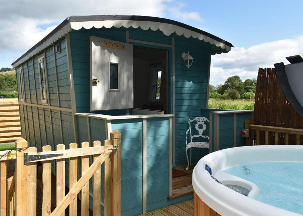 a small blue shack with a bath tub on a deck at Riverview Lodges And Glamping in Welshpool