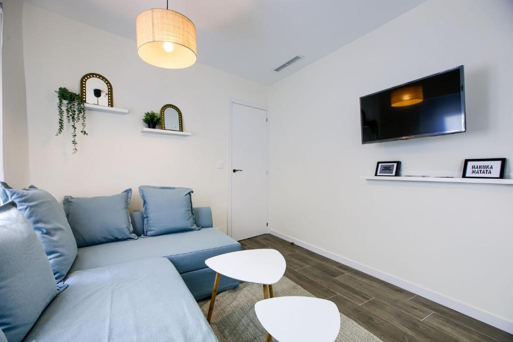 a living room with a blue couch and a tv at CASA MARMEL Plaza Castilla in Madrid