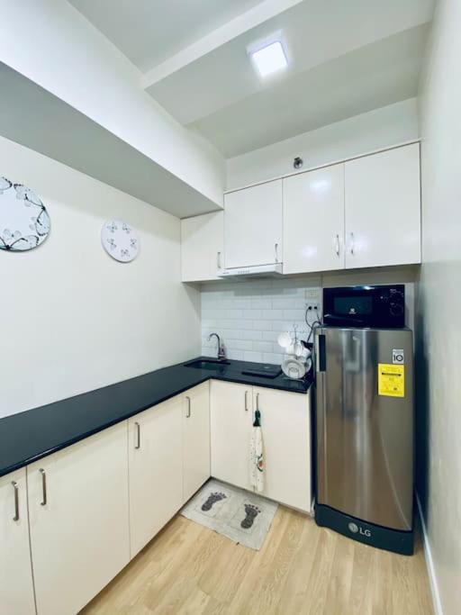 a kitchen with white cabinets and a stainless steel refrigerator at Functional 1-br Space in Amaia with Fast Internet in Mandaue City