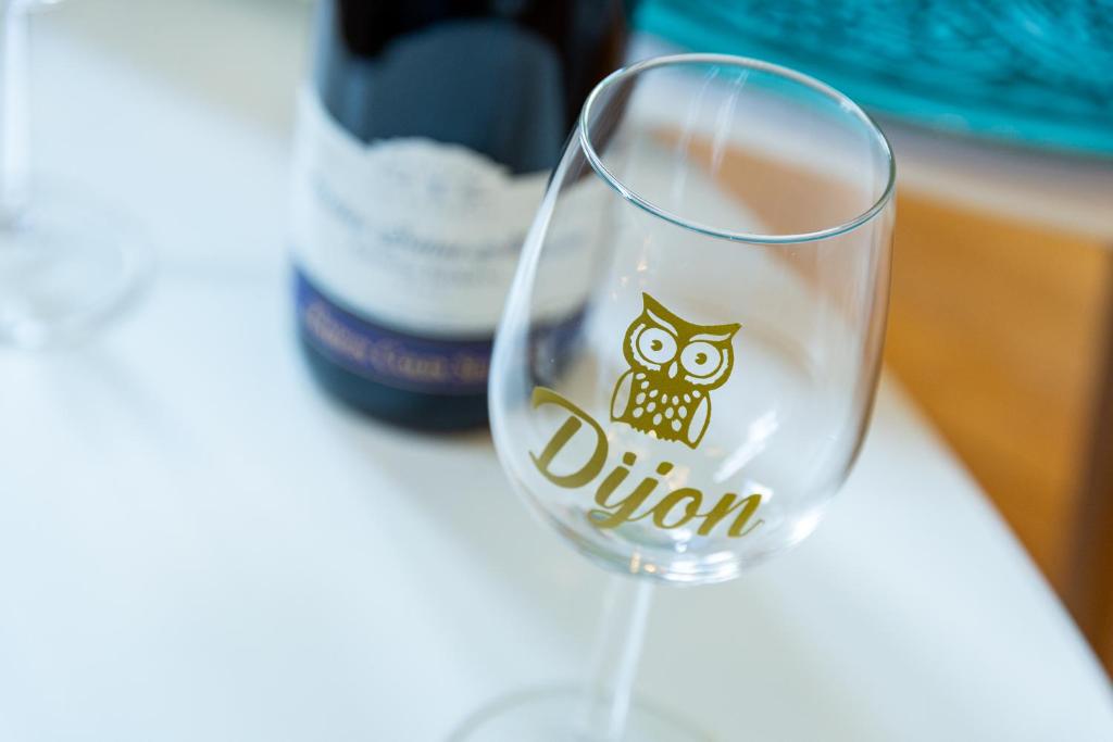 a wine glass with an owl on it next to a bottle at Côté Cour - Centre Ville- Calme - Charme - 4 Voyageurs in Dijon