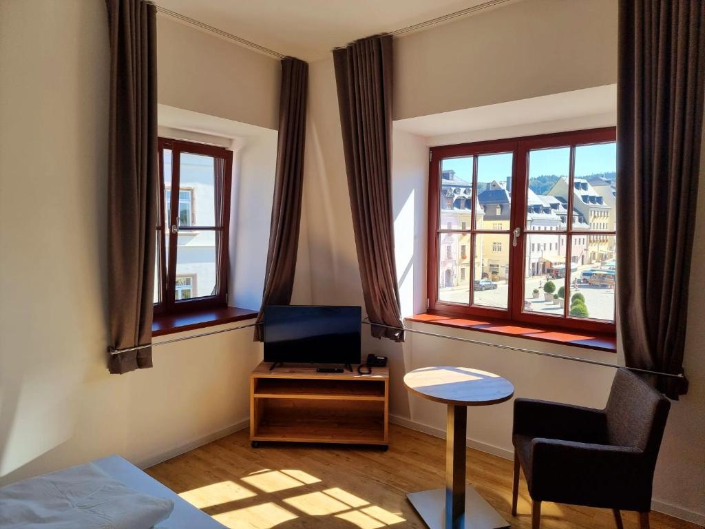 um quarto com uma cama, uma televisão e janelas em Pension Rio em Schneeberg