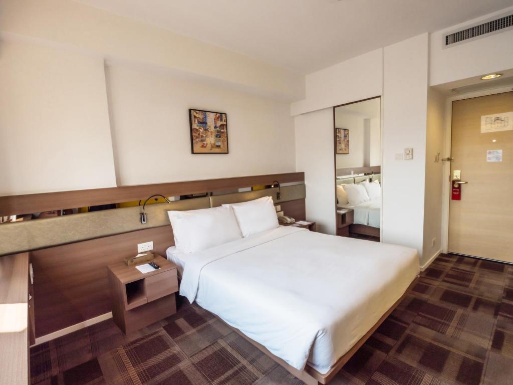 ein Hotelzimmer mit einem Bett und einem Spiegel in der Unterkunft Travelodge Kowloon in Hongkong