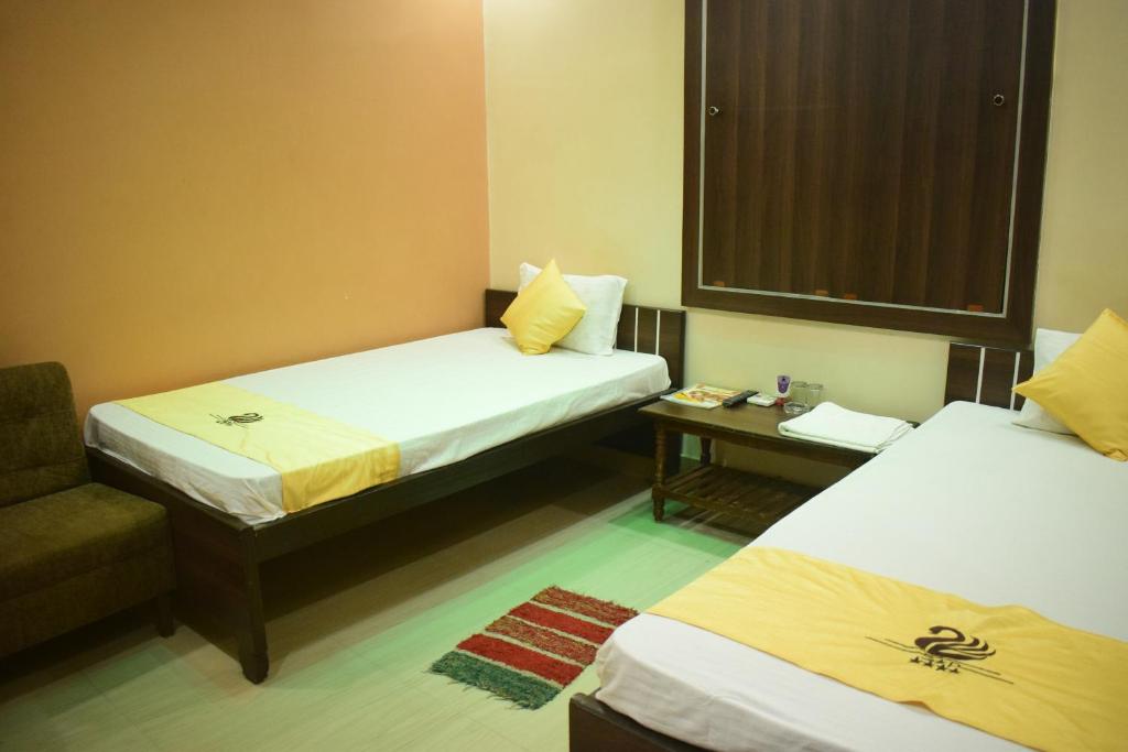 a hotel room with two beds and a chair at Hotel Shakuntla Palace in Gaya