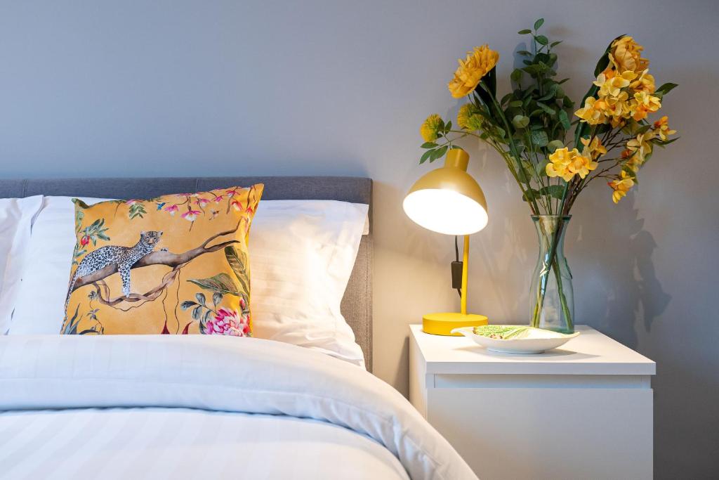 Un jarrón de flores en una mesita de noche junto a una cama en Lovely 3-bedroom flat with free parking, en Bridge of Allan