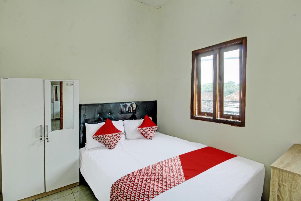 1 dormitorio con 1 cama con almohadas rojas y blancas en OYO Life 92312 A+ Cozy Rooms Syariah, en Kediri