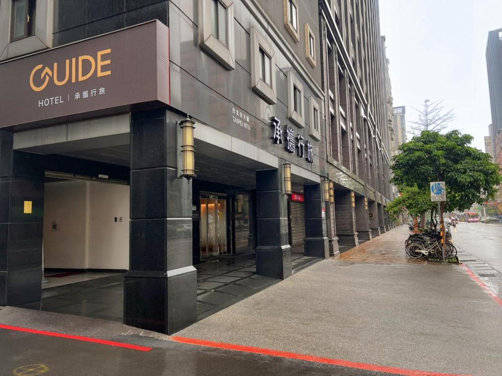 a building on a street with a motorcycle parked outside at Guide Hotel Taipei NTU in Taipei