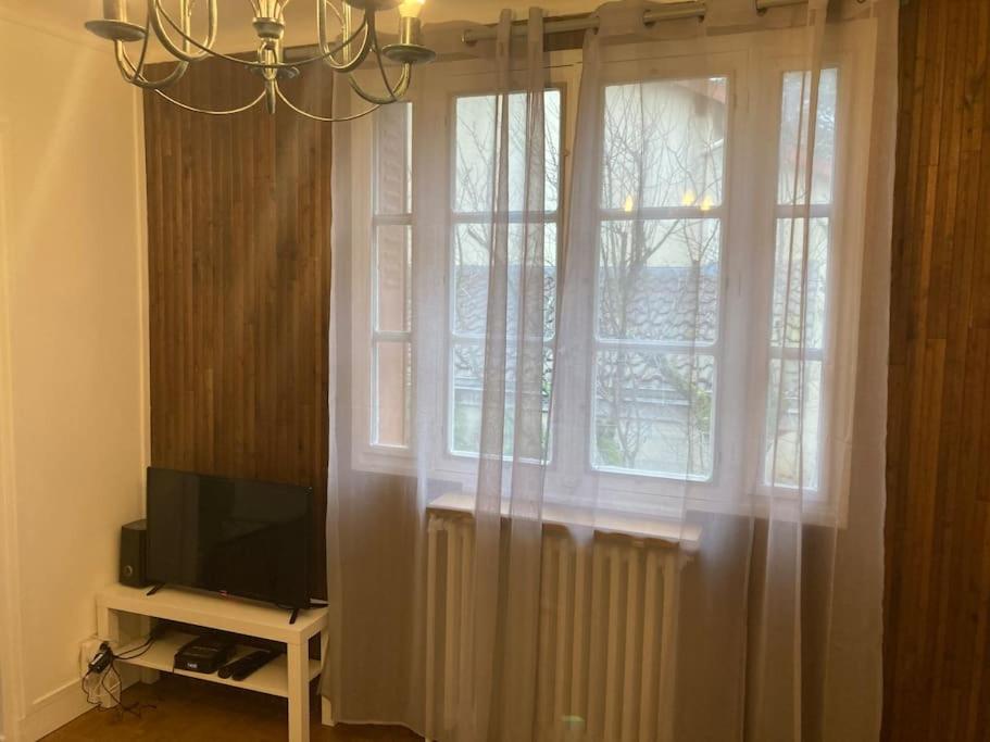 a living room with a window and a television at Idéal 4 pièces, tout confort in Courcouronnes