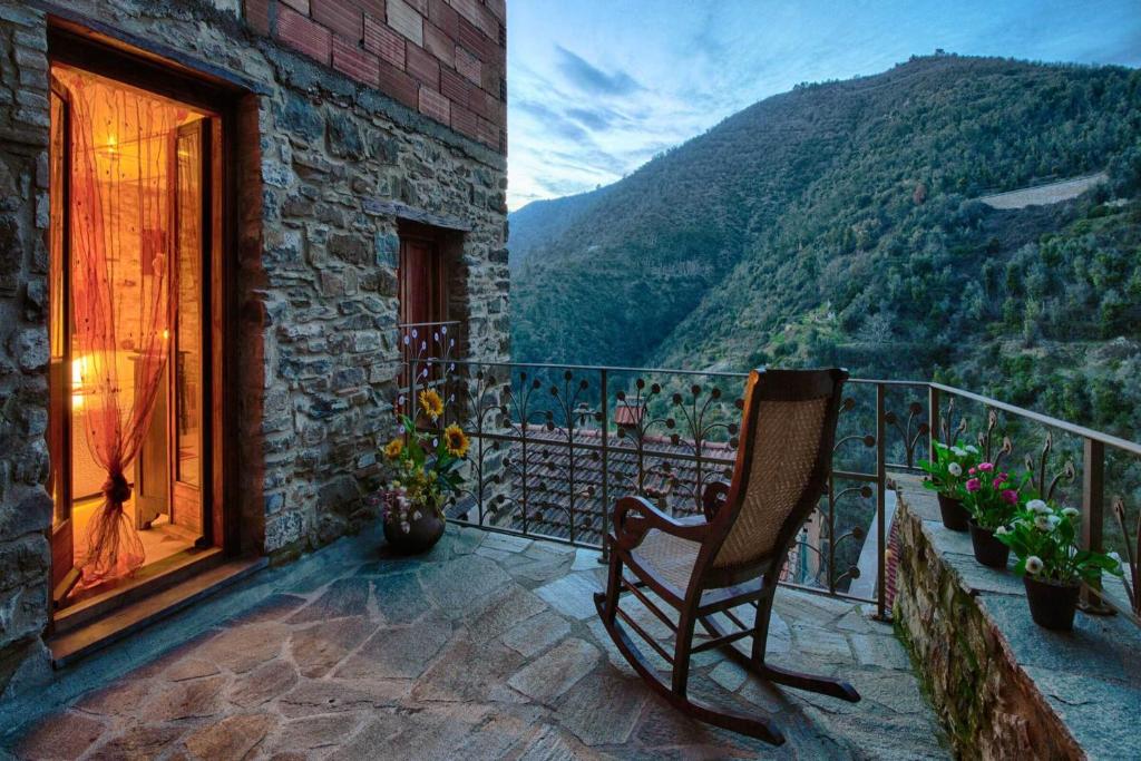a chair on a balcony with a view of a mountain at Apartments In The Heart of Medieval Village - Happy Rentals in Apricale