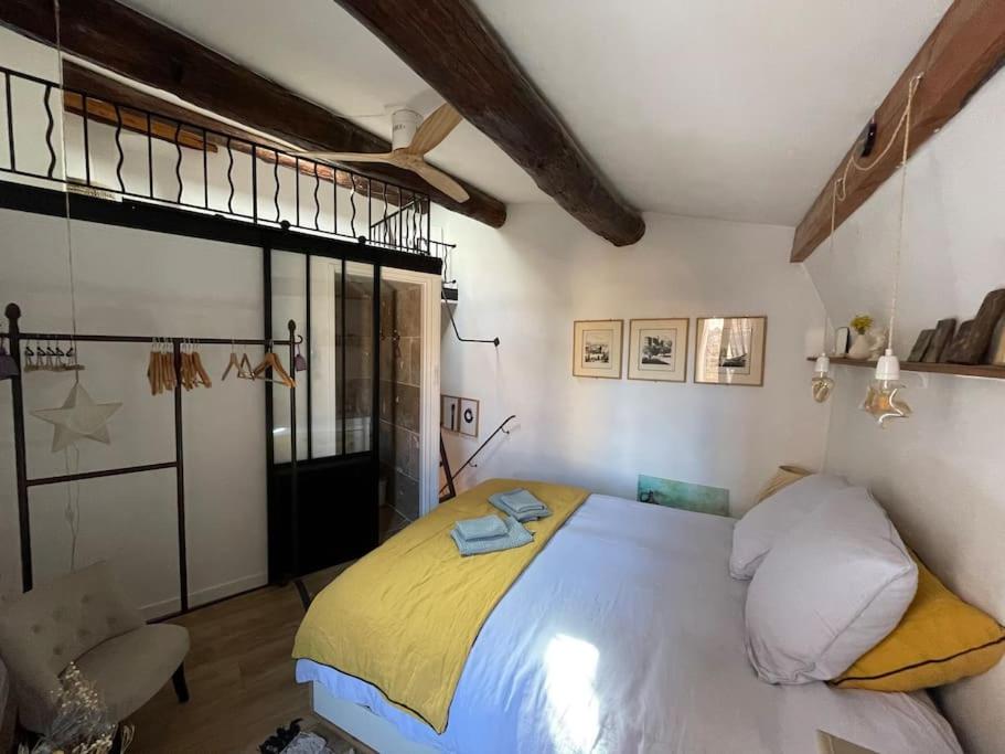 a bedroom with a large bed with a yellow blanket at Duplex Atelier / coeur de Lourmarin in Lourmarin