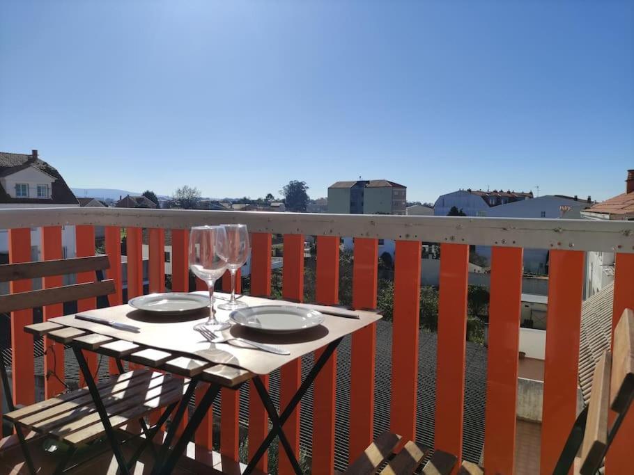 a table with two glasses of wine on a balcony at Boa Vista Playa As Sinas en Vilanova de Arousa in Villanueva de Arosa