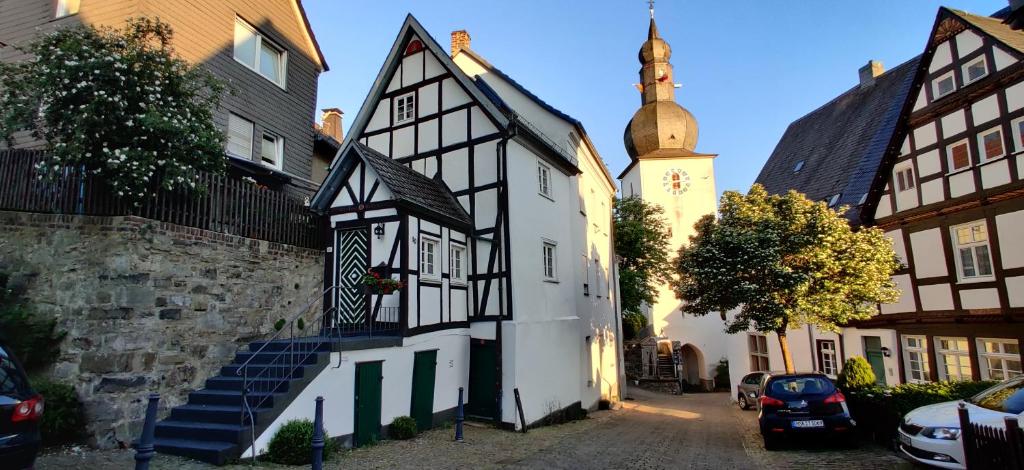 a black and white building with a church in the background at 300 Jahre altes Haus in der historischen Altstadt in Arnsberg