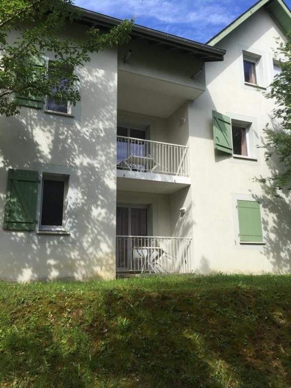 um edifício branco com persianas verdes e um quintal em Appartement cozy pour curistes et touristes em Salies-de-Béarn