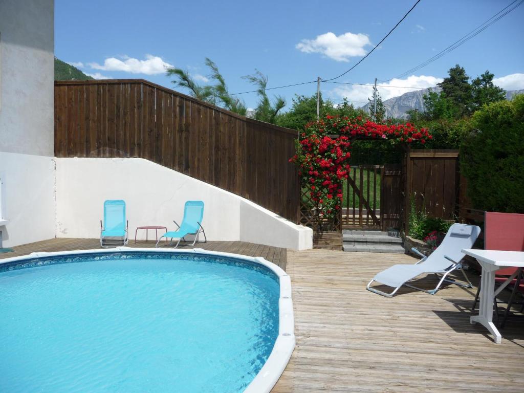 un patio trasero con piscina, sillas y mesa en Le Glandasse, en Die