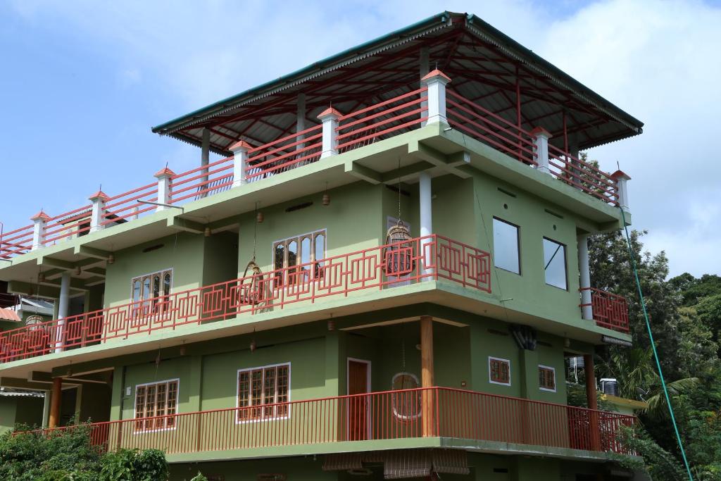 a green building with red balconies on top of it at Panthalams Homestay in Thekkady